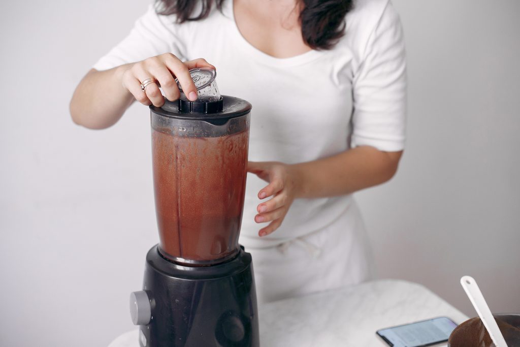 A barista making a blended frozen coffee behind the counter.