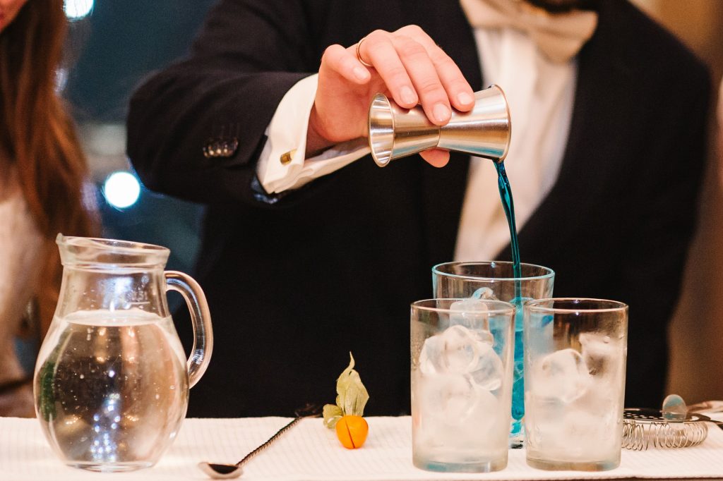 Bartender pouring fruit concentrate into a glass of ice before topping with soda