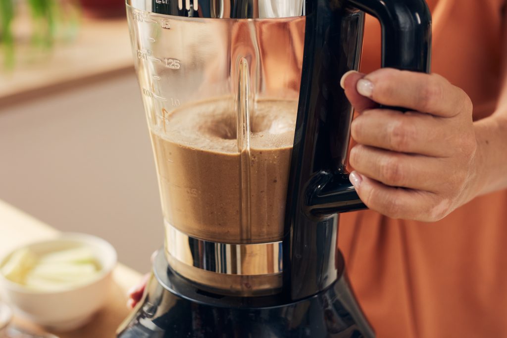Creamy blended coffee pouring from a blender pitcher into a tall glass
